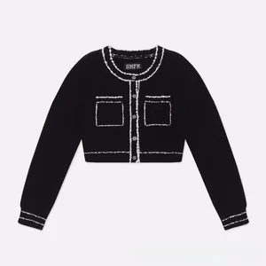 Detail view of the contrast trim, decorative pockets and metallic buttons on the black jacket