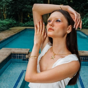 Fashionable 18k gold starfish necklace and pearl bracelet set shown on model by the pool