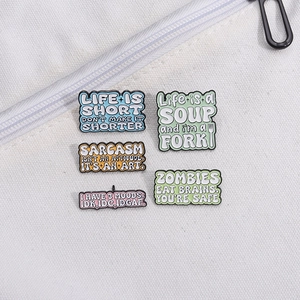 Set of five creative enamel alphabet pins with humorous phrases on white canvas bag