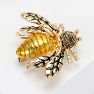 Detail of honey bee brooch with golden enamel wings and intricate metal texture