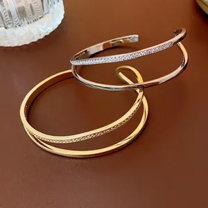 Double-layer open bangle with cubic zirconia in gold and silver finish with polished band