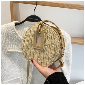 Detail of round straw bag showing wheat weave texture and floral embroidery