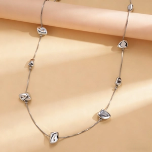 Detailed close-up of a silver minimalist sweater necklace with irregular geometric beads