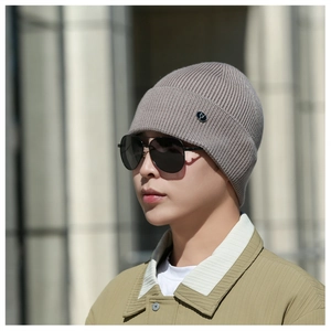 Close-up of knit beanie with ear protection, metal logo badge and vertical ribbed texture