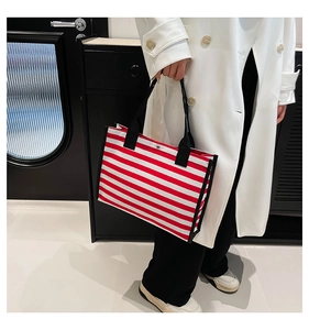 Dettaglio della borsa tote in tela a righe rosse e bianche con manici neri e fibbia in metallo