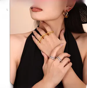 Close-up of snake-shaped rings with grid texture and gold hoop earrings on model