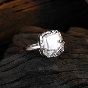 Anello con perla barocca quadrata e castone in argento irregolare su legno scuro
