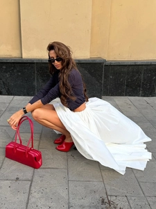 Detail of white maxi skirt featuring high-volume pleated hem and elegant trailing silhouette
