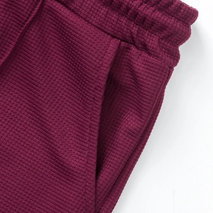 Detalle de pantalones cortos burdeos en punto gofrado con cintura elástica y bolsillo