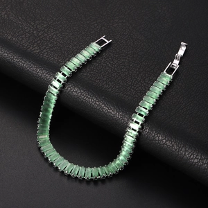 Close-up of silver tennis bracelet with emerald green rectangular cut zircon stones
