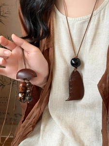 Détail d'un collier pendentif en bois ethnique aux textures naturelles sur lin