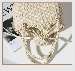 Détail d'un sac à main en paille beige avec doublure en toile à cordon et anse tressée