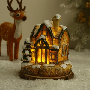 Gros plan du chalet de Noël lumineux avec neige artificielle sur socle en bois