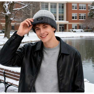 Close-up of gray knitted winter beanie with LA&DH label on a snow-covered outdoor background