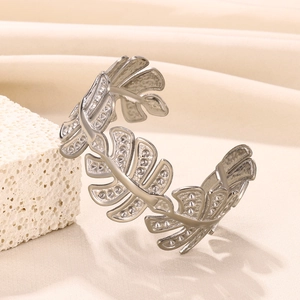 Close-up of a silver open cuff bracelet featuring double-layered leaf textured cutouts