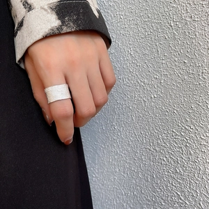Close-up of a wide 925 sterling silver ring with brushed metal texture worn on a finger
