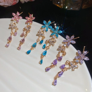 Macro shot of silver needle floral earrings with rhinestones in pink, blue, and purple