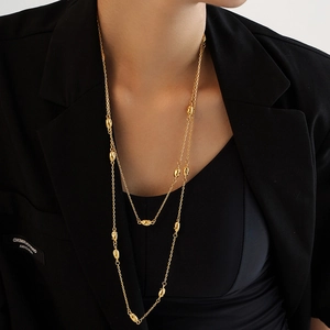 Double-layered gold titanium necklace with irregular beads worn on a black suit