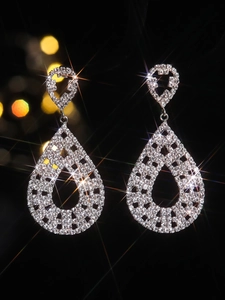 Macro shot of silver drop earrings with pavé rhinestones on a dark elegant background