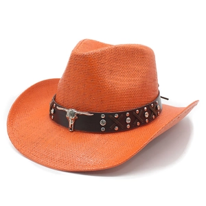 Détail du chapeau de cowboy en paille orange avec emblème de tête de taureau et cuir clouté