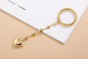 Detail view of a gold heart beaded keychain with heart pendants on a beige background