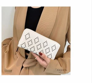 Detail einer weißen Lederclutch mit Rauten-Nietmuster, von einem Modell gehalten