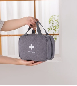 Portable gray first aid bag with handle and white cross logo for travel medicine storage