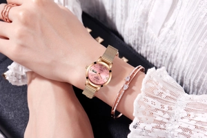 Close-up of rose gold quartz watch with pink dial and milanese mesh band on wrist