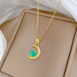 Detail of crescent moon pendant with green heart gemstone and sparkling pavé diamonds