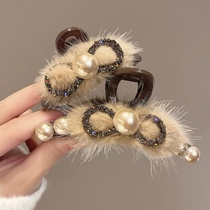 Detail of plush bow hair clips featuring champagne faux fur, pearls, and rhinestones