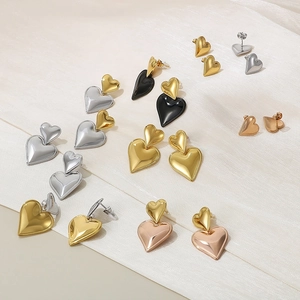 Detailed view of 18K gold and silver heart stud earrings on beige fabric background