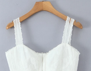 Close-up of intricate floral embroidery and delicate lace texture on a white camisole