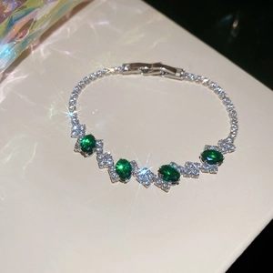 Detail of luxury butterfly bracelet with emerald green stones and sparkling zircons
