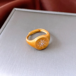 Macro detail of gold starburst ring with zircon inlay and brushed metal texture finish