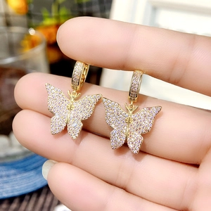 Close-up of gold butterfly earrings with sparkling pink and rainbow pavé zircons