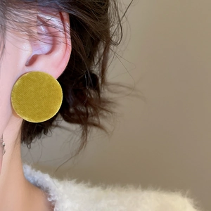 Close-up of model wearing yellow velvet round stud earrings for a vintage soft look
