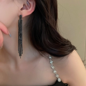 Gros plan de boucles d'oreilles noires à franges géométriques portées par un modèle