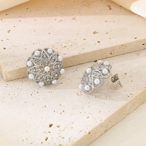 Close-up of vintage hollow silver earrings with white pearls and sparkling diamonds