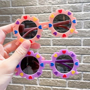 Detail of pink and purple floral wavy round frame sunglasses with colorful heart accents