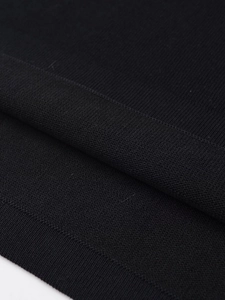 Macro shot of fine black knitted fabric showing premium texture and ribbed hem detail