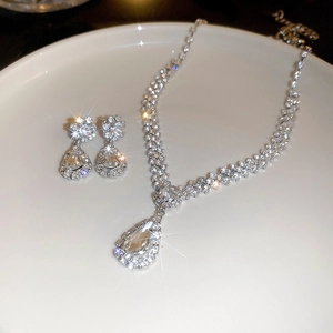 Close-up of sparkling teardrop V-shape necklace and earring set with shimmering crystals