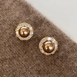 Detailed view of vintage pearl earrings with zircon halo on brown knit sweater