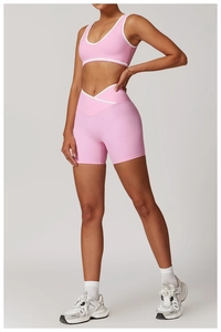 Close-up of pink yoga set with white trim, high waist cross belt and U-neck vest detail