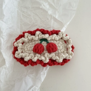 Detail of hand-knitted crochet flower hair clip with cherry pattern and scalloped edges
