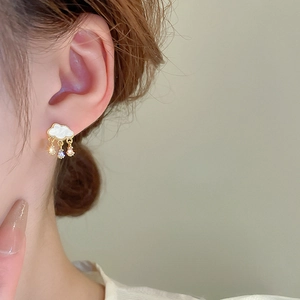 Close-up of cloud-shaped gold earrings with mother-of-pearl and dangling crystals
