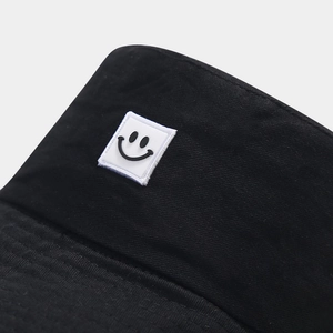 Close-up of a smiley face patch on a black twill cotton sun bucket hat for outdoor protection