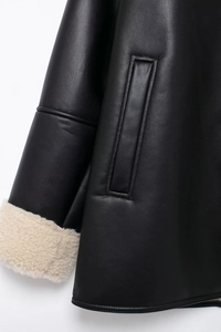 Detailed view of black leather jacket featuring contrast faux shearling cuffs and stitching