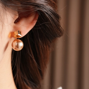 Detail of vintage round pearl drop earring with yellow crystal on a female model