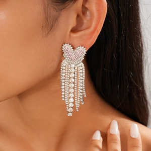Detail of pink crystal heart earrings with sparkling silver fringe tassels worn by model