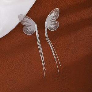 Detail of silver butterfly earring featuring intricate hollow wings and long fine tassels